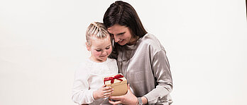 Eine Mama und ein Mädchen freuen sich über ein Geschenk.
